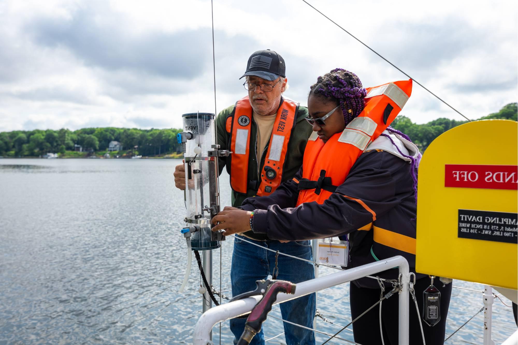 在D号游轮上，一名学生和一名水手在收集春湖的水样本.J. 安格斯